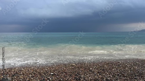 Sea waves crashing on pebble beach under dark stormy sky with ambient nature sound