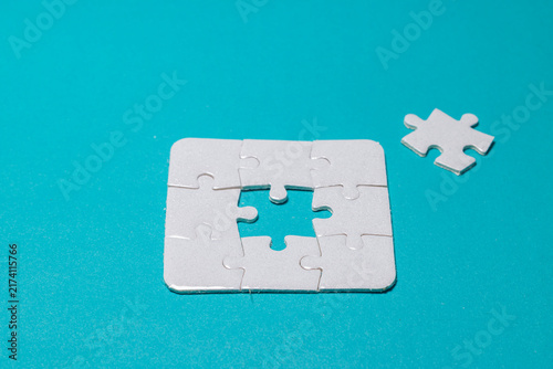 Konstfotografi White jigsaw puzzle set with one missing piece in the center isolated on bright cyan background, representing business strategy, solution, and teamwork success