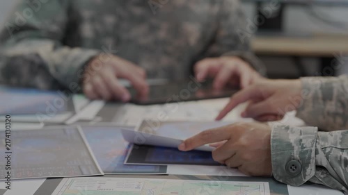 Military officers analyzing tactical map documents and digital tablet in command war room