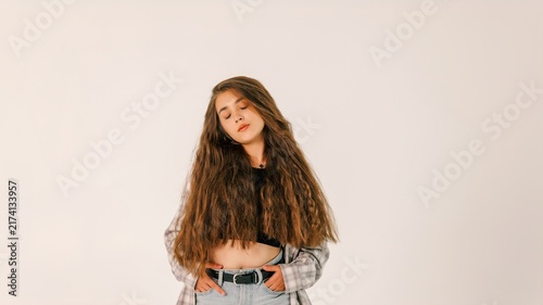 Young woman with long, voluminous, crimped hair posing with hands in pockets
