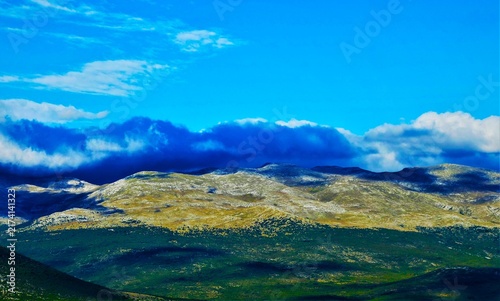 Obraz na płótnie Blue fluffy clouds above the mountain valley horizon in wonderful green nature