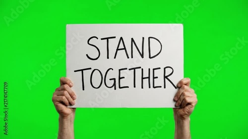 Hands holding a banner sign with the text stand together on a green screen chroma key background