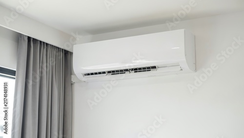 Modern wall mounted air conditioning unit installed in a clean minimalist bedroom interior