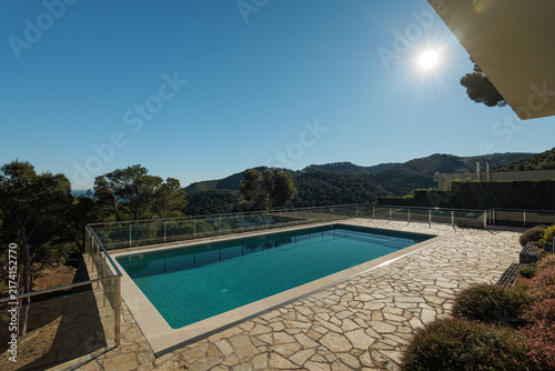 Modern outdoor swimming pool with stone deck and mountain view under clear blue sky