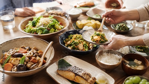 健康的な和食が並ぶ食卓で料理を取り分ける家族の団らん風景