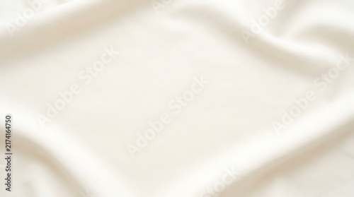A close up view of a soft white fabric texture showing delicate folds and smooth waves of elegant material background