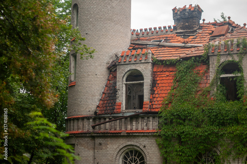 Abandoned overgrown mansion with spiral staircase, old car and ruined interior