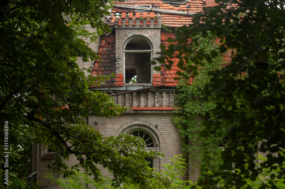 Obraz premium Abandoned overgrown mansion with spiral staircase, old car and ruined interior