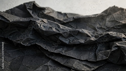 Close-up textured view of crumpled black paper, revealing intricate folds and shadows