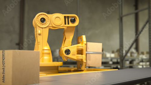 Yellow robotic arm holding a cardboard box on a conveyor belt in a warehouse with shelves in the background.