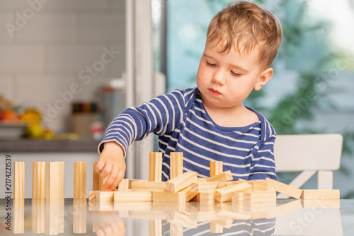 Plakat Young builder proudly sitting behind his wooden constructions.