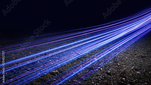 Streaks of vibrant blue and purple light surge across a dark, textured surface