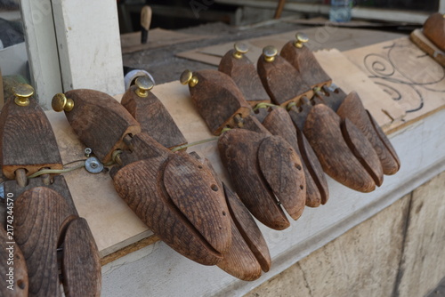 Row of vintage wooden shoe lasts and cobbler forms on bench for shoemaking background and craft workshop display
