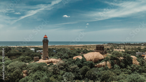 Bild auf Leinwand Old lighthouse rising above ancient temples and coastal greenery