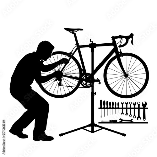 Bicycle mechanic repairing road bike on repair stand with tool rack silhouette