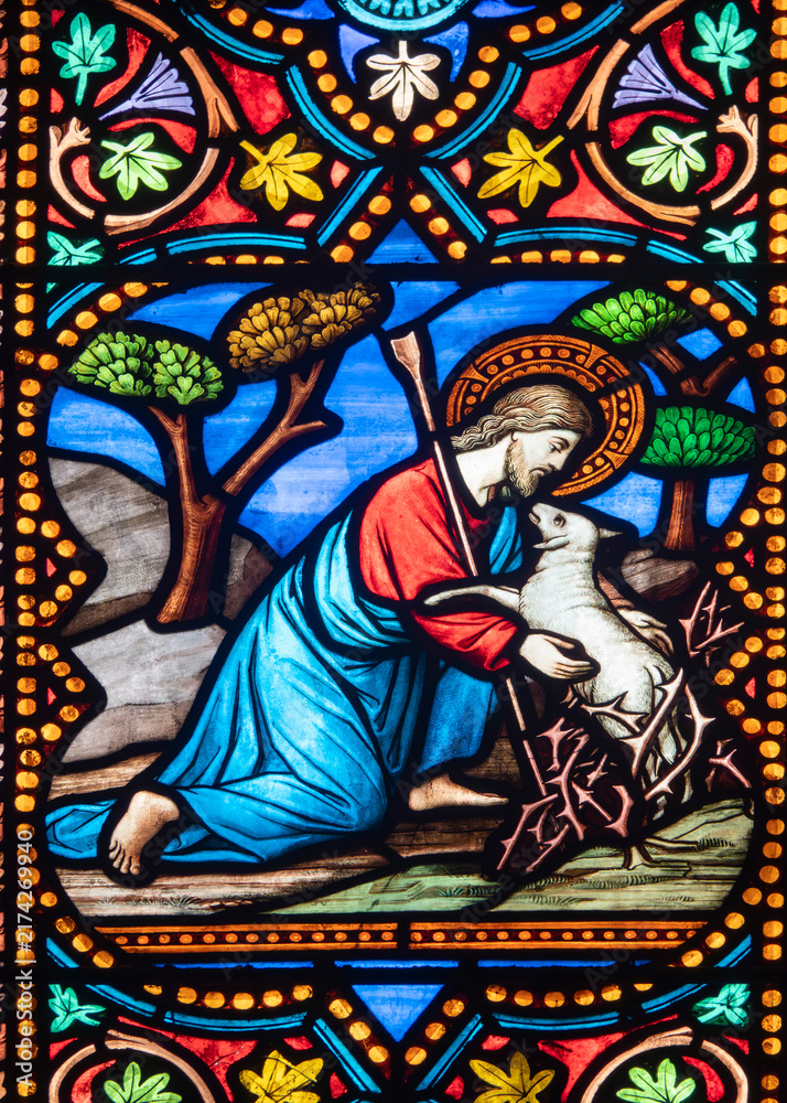 Obraz premium Jesus Christ rescues a trapped lamb from thorny bushes in a colorful stained glass window detail.