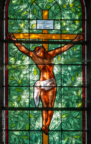 Fotografía A stained glass window depicts Jesus Christ on the cross with a green foliage background