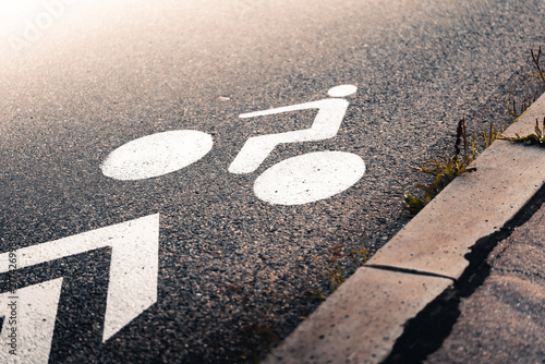 Quadro su tela White bicycle lane sign painted on asphalt road surface at sunset