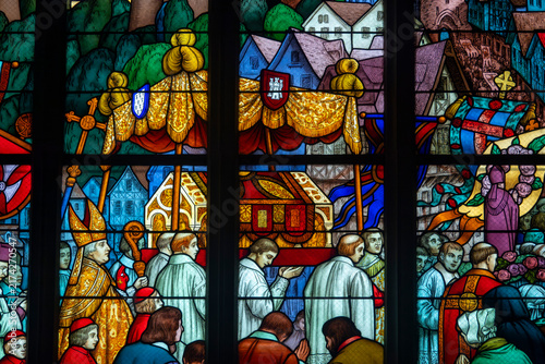 Foto Clergy members and townspeople carry a relic chest during a procession depicted in stained glass