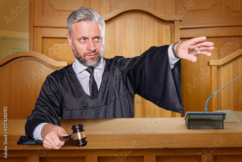 Foto Judge with Gavel Pointing in Wood-Paneled Courtroom