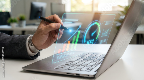 Hand with pen pointing at holographic KPI growth chart