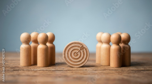 Wooden business figures gathered around dartboard target
