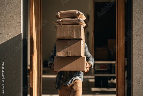 Person Carrying Multiple Packed Boxes and Bags in Doorway During Moving Process