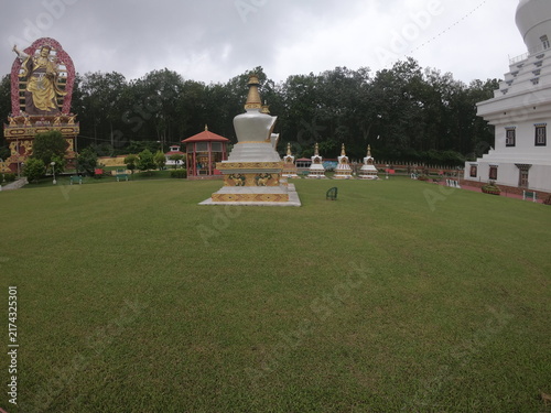 Fotografie A peaceful outdoor view of a Buddhist monument or Buddha statue situated in a landscaped garden