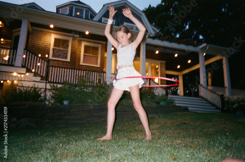 Young Girl with hula hoop in backyard of home film dusk