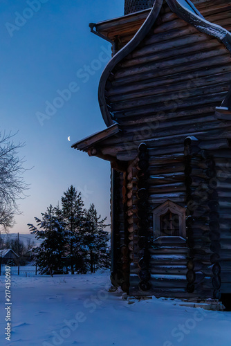 Obraz na plátně Ancient log Church of the Intercession with a barrel roof under a crescent moon in evening winter Zaostrovie, Arkhangelsk oblast, Russia