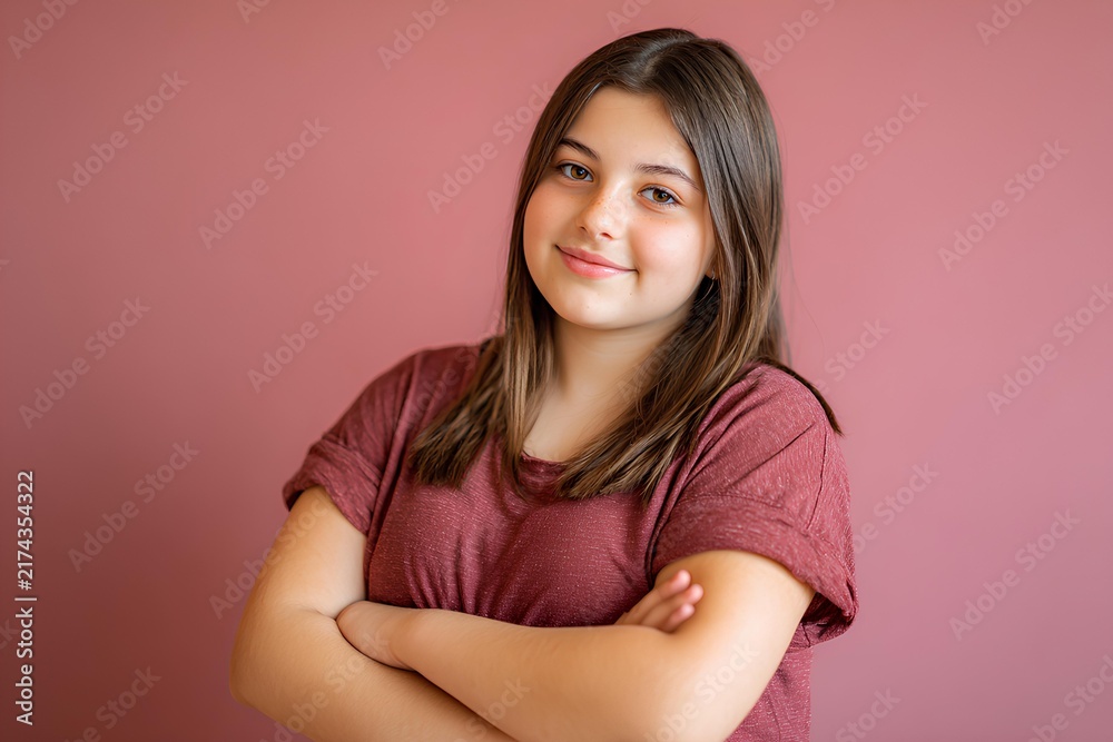 Obraz premium Plus-size Latina girl with long hair in a t-shirt smiling brightly against pink background, radiating joy, confidence, and youthful energy.