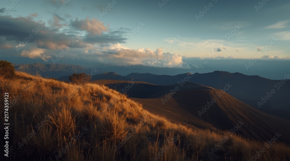 Obraz premium Dramatic Volcanic Crater Landscape at Sunset with Golden Grass and Mountains