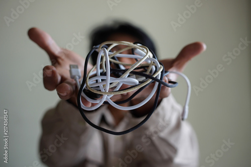 Close-up of a tangled bundle of electronic cables presented toward the camera, representing cable clutter, technology overload, connectivity problems, and disorganized accessories