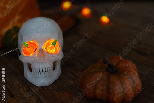 Obraz na plátně Glowing Orange-Eyed Skull Prop with Pumpkins for Eerie Halloween Decor Display