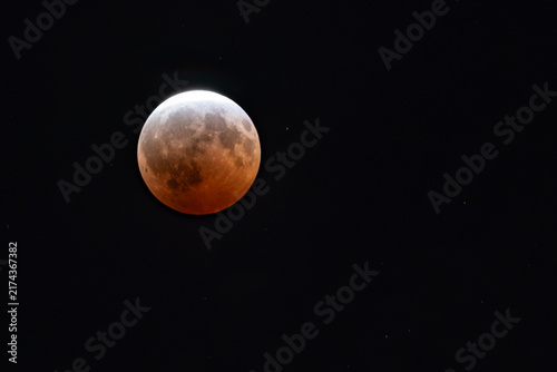 Partial blood moon lunar eclipse isolated on black in the night sky with copy space 