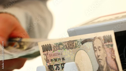 Japan Yen vs. US dollar exchange rate. Business and financial concept. Currency relationships. Japanese and US money. Japanese yen counter and businessman counting dollars.

