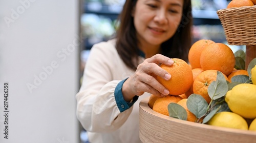 Woman choosing fresh oranges at a grocery store produce section,There is copy space on the left side of the frame.
