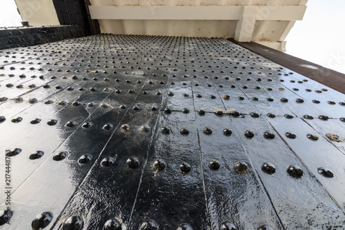 Bild auf Leinwand A close-up view of a weathered metal surface with riveted plates arranged in a g
