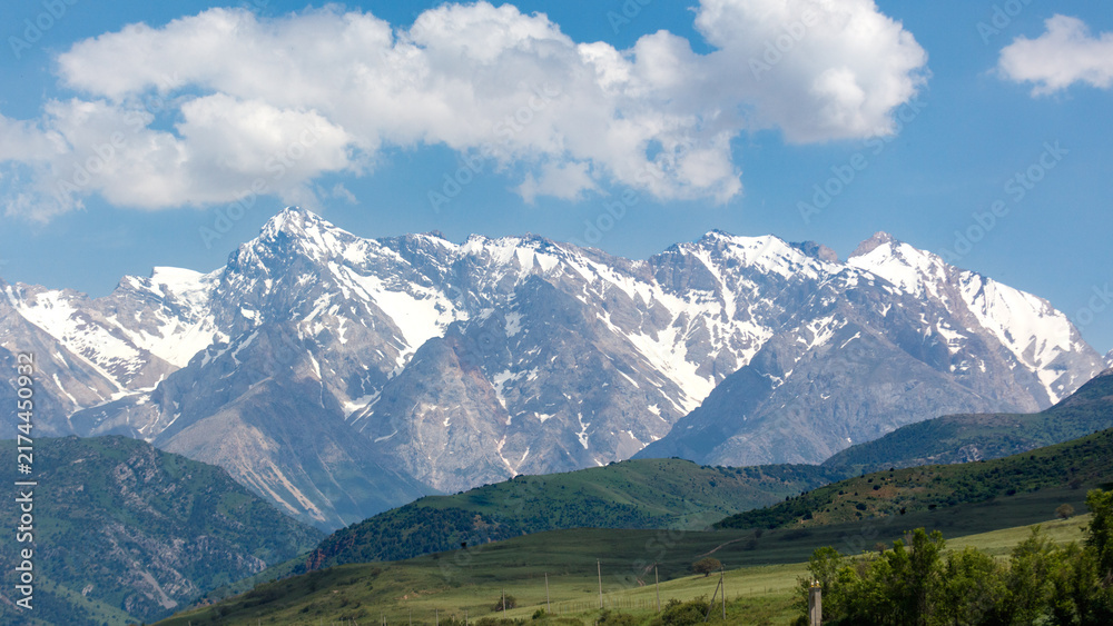 Naklejka premium Snow-capped mountains rise above green valleys