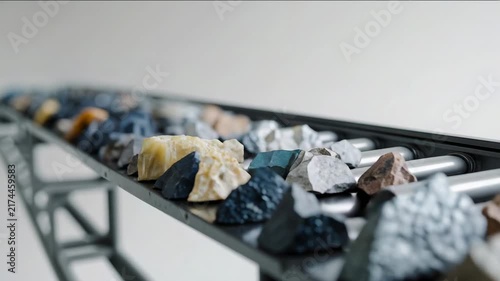 Different types of rocks are displayed on a conveyor belt in a storage area