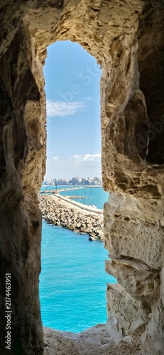 View of the Mediterranean Sea through an ancient stone window in the Qaitbay Citadel, a 15th-century defensive fortress located on the Mediterranean coast, on Pharos Island in Alexandria, Egypt.