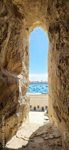 View of the Mediterranean Sea through an ancient stone window in the Qaitbay Citadel, a 15th-century defensive fortress located on the Mediterranean coast, on Pharos Island in Alexandria, Egypt.