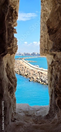 View of the Mediterranean Sea through an ancient stone window in the Qaitbay Citadel, a 15th-century defensive fortress located on the Mediterranean coast, on Pharos Island in Alexandria, Egypt.
