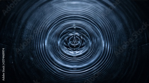 Water drop creating large ripple texture across a body of water