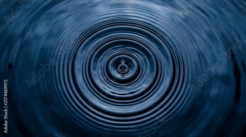 Water drop creating large ripple texture across a body of water