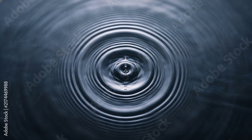 Water drop creating large ripple texture across a body of water