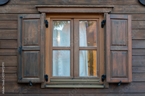 Rustic wooden window with open shutters on cabin exterior wall
