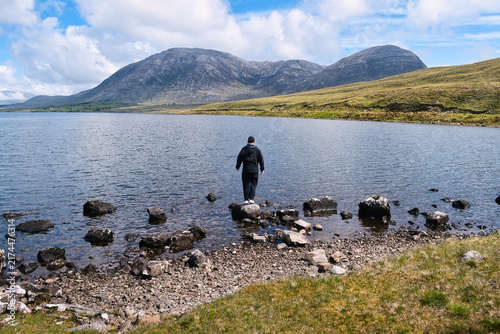 Quadro su tela Man standing at Lough Inagh in Connemara National Park, Galway, Ireland with roc