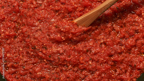 Foto Isolated Homemade Tomato Sauce with Chunky Vegetables and Herbs Stirred by Woode