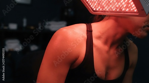 Woman receiving red light therapy treatment on her shoulder to help with muscle pain relief and skin health care